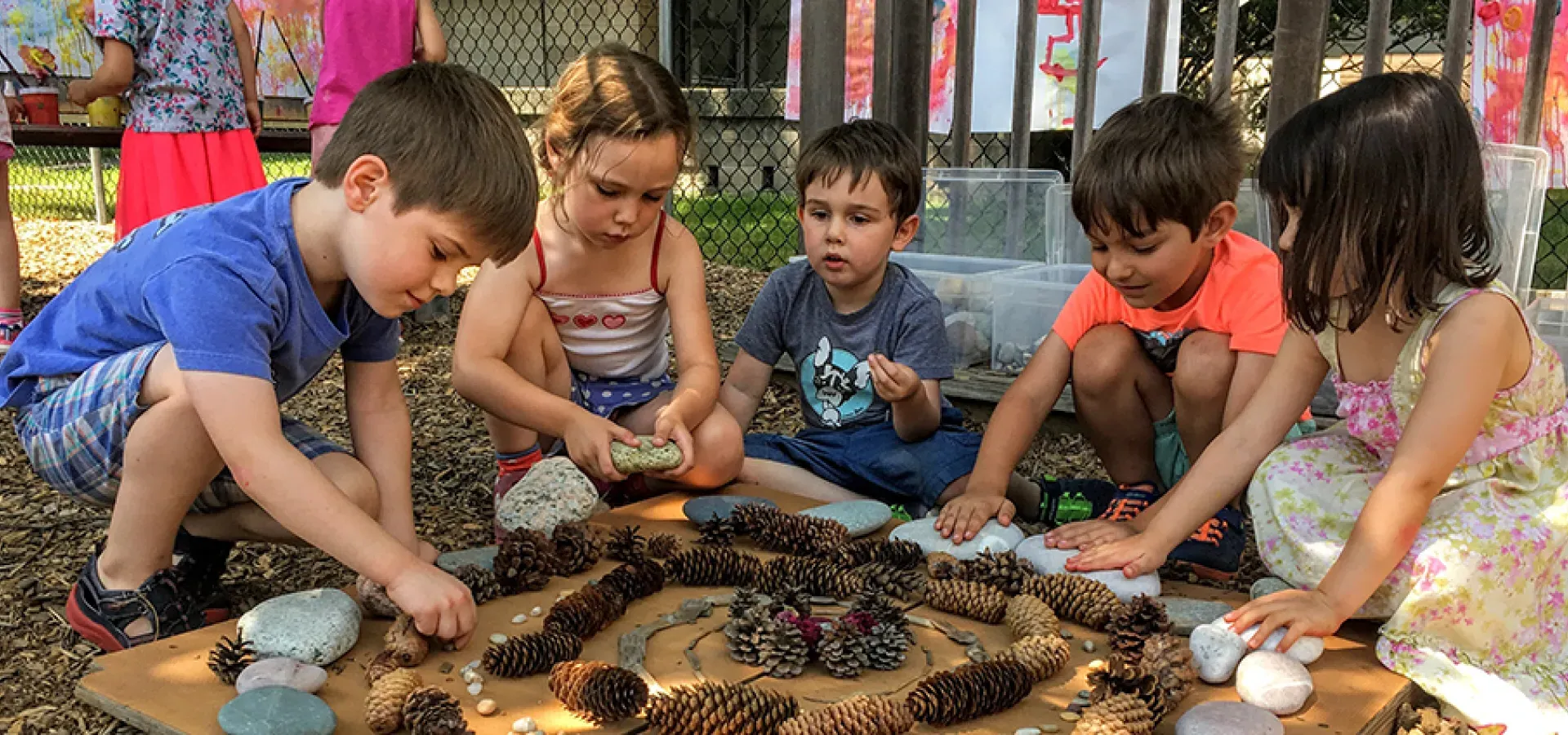 Group of young children making art from pinecones