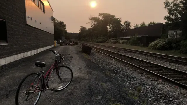 Bicycle near train tracks with sun setting by Liliana Wollheim Martinez